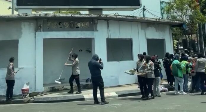 Anggota Kepolisian sedang lakukan cat ulang pos polisi ciceri yang dirusak massa aksi.